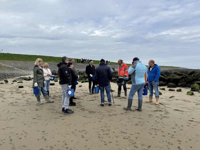 Groep met emmers aan zee tijdens een uitje op het strand